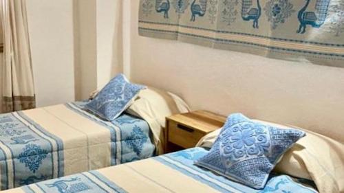 a room with two beds with blue and white pillows at AZIENDA AGRITURISTICA S'ARGALASI - B&B - AFFITTACAMERE Loc S'Argalasi Austis in Austis