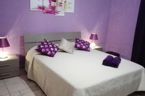 een slaapkamer met 2 bedden met paarse muren en 2 lampen bij Home away from Home in Żurrieq