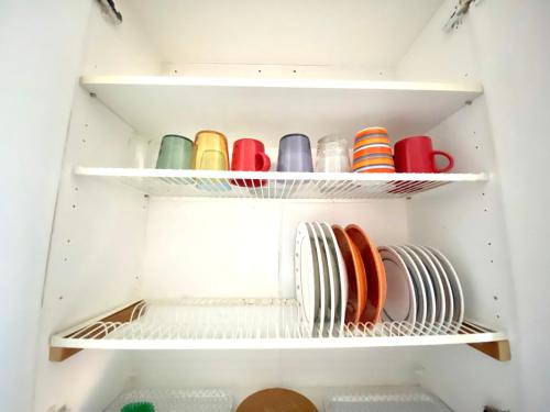 a closet with plates and bowls on shelves at Cozy nest in the heart of Helsinki in Helsinki