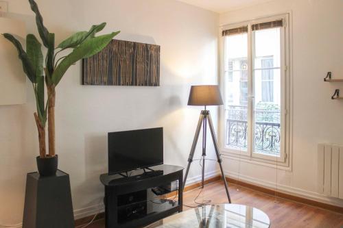un salon avec une télévision et une plante en pot dans l'établissement Pretty love nest close to Père-Lachaise, à Paris