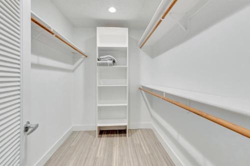 a hallway with white walls and stairs with white shelves at Idyllic Boca Pool Home: 4/2.5 + Study-FAU & Mizner in Boca Raton