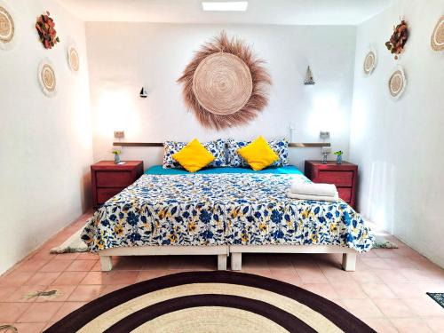 a bedroom with a bed with blue and yellow pillows at Casa Isabella in Cozumel