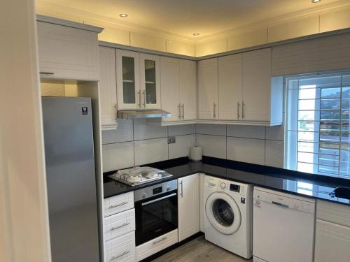 cocina con armarios blancos, lavadora y secadora en After 5 Apartment 3 2 spacious en-suite bedrooms, en Freetown