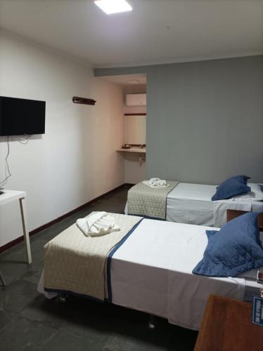 a hotel room with two beds and a television at Pousada A Pérola in Rio de Contas