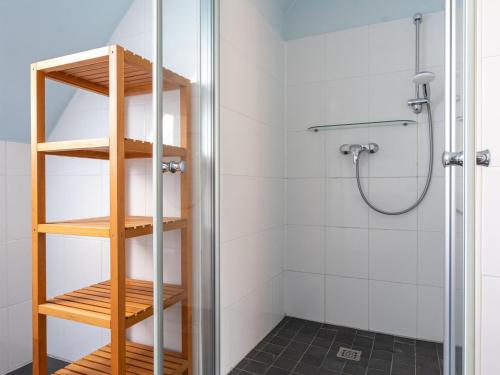La salle de bains est pourvue d'une douche et d'une étagère en bois. dans l'établissement Cozy Apartment in Bastorf with Garden, à Bastorf