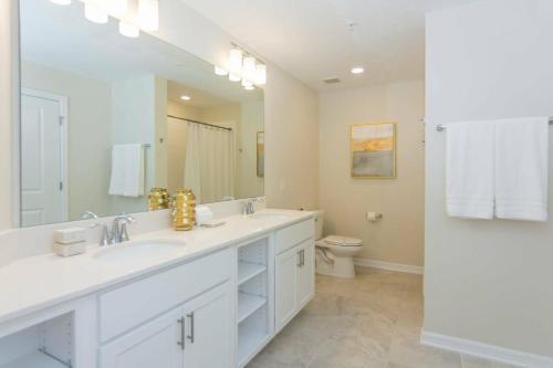 uma casa de banho branca com 2 lavatórios e um WC em Awesome Apartment at Storey Lake SL47318 em Kissimmee