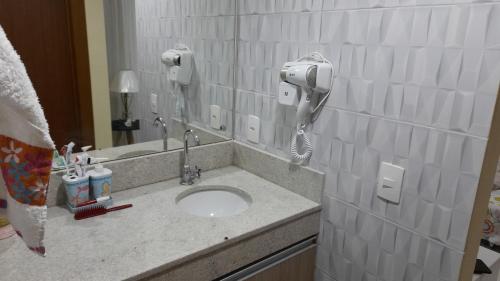 Aldeia das Aguas Quartier في بارا دو بيراي: حمام مع حوض وهاتف على الحائط