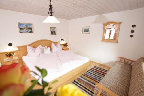 a bedroom with a white bed and a couch at Maurerhof in Ruhpolding