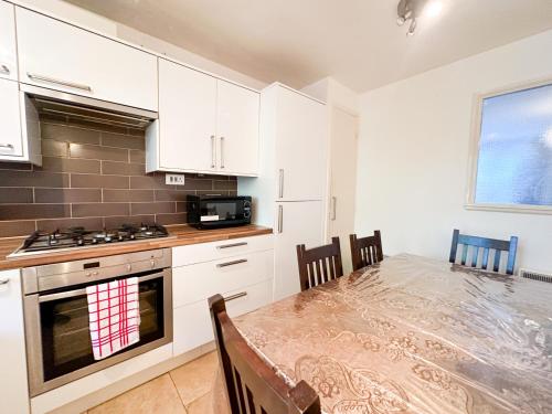 a kitchen with white cabinets and a table with chairs at 36 O’Leary square in London