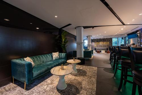 a bar with a green couch and tables and chairs at Albion Hotel in Miami Beach