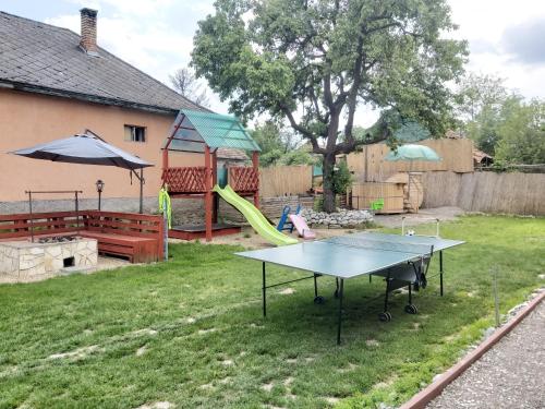 a ping pong table in a yard with a playground at Sweet Home Apartman Szilvásvárad in Szilvásvárad