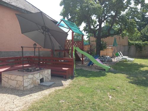 a park with a bench and an umbrella and a playground at Sweet Home Apartman Szilvásvárad in Szilvásvárad