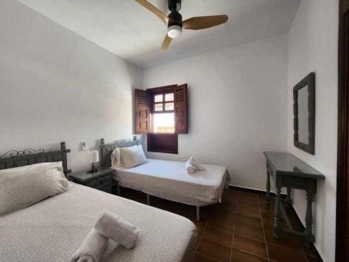 a bedroom with two beds and a ceiling fan at Villa Salada on the Ocean Shore in Caleta De Fuste