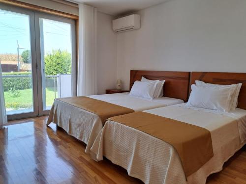a bedroom with two beds and a large window at CasaAnabela in Póvoa de Varzim