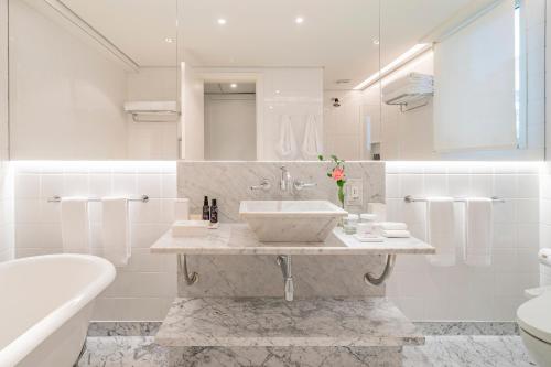een badkamer met een wastafel, een toilet en een bad bij Hotel Emiliano in Sao Paulo