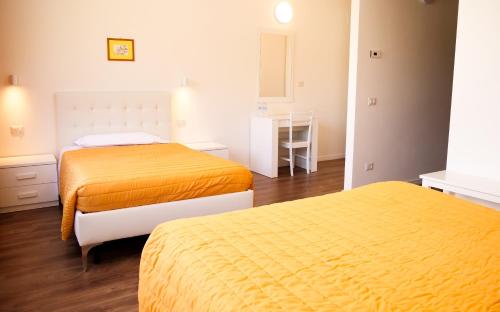 two beds in a room with orange sheets at Victoria Royal Garden in Como