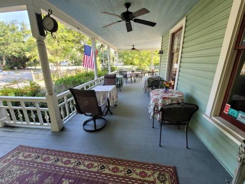 un porche con mesas y sillas y una bandera americana en Anticipation Room in Camellia Rose Inn Downtown, en Gainesville