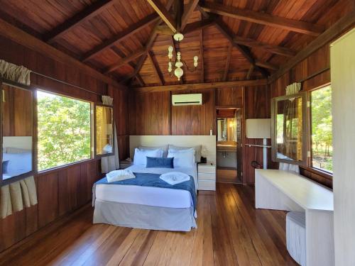 Schlafzimmer mit einem Bett, Holzwänden und Holzböden in der Unterkunft Pobore SPA Pousada in Rondonópolis