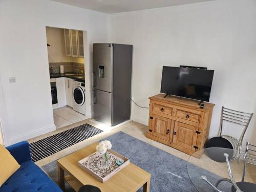 a living room with a refrigerator and a tv at Your Own Ground Floor Apartment in Central Woking in Woking