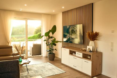 sala de estar con TV de pantalla plana en un soporte en 118qm Traumzeit Residences am National Park Birkenfeld - Perfekt für bis zu 4 Personen en Ellweiler