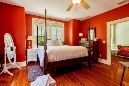1 dormitorio con paredes rojas, 1 cama y ventilador en Briar Rose Room at Camellia Rose Inn Downtown, en Gainesville