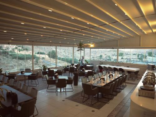 a restaurant with tables and chairs in a room with large windows at Petra Boutique Hotel in Wadi Musa