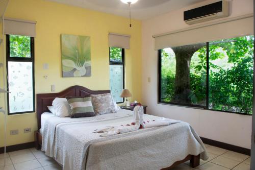 1 dormitorio con 1 cama con sábanas blancas y ventanas en Apartments-Villas Playa Potrero 1, en Potrero
