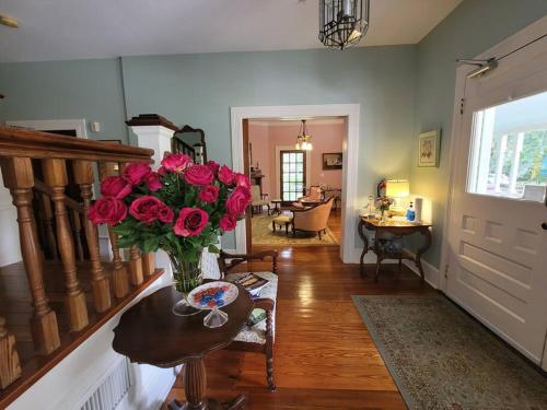 een woonkamer met een vaas van rozen op een tafel bij Lady Clare Room at Camellia Rose Inn Downtown in Gainesville