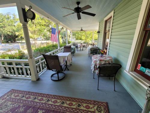 een veranda met tafels en stoelen en een Amerikaanse vlag bij Lady Clare Room at Camellia Rose Inn Downtown in Gainesville