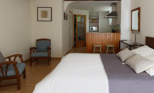 a bedroom with a large white bed and a kitchen at maison La Marche in Cugand