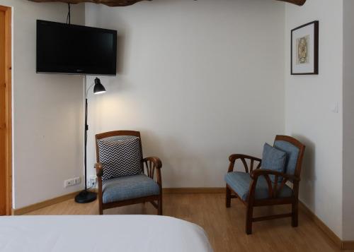 a bedroom with two chairs and a flat screen tv at maison La Marche in Cugand