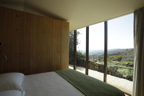 a bedroom with a bed and a large glass window at Gerês - Leiras do Tempo - Cottages in Brufe