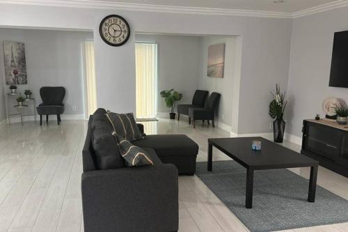 uma sala de estar com um sofá, uma mesa e um relógio em House w/ 3 bedrooms/pool/garden em Margate