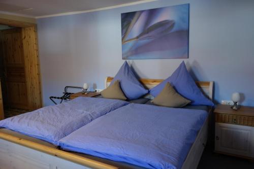 a bedroom with a bed with blue sheets and a painting at Zehnthof in Geldersheim