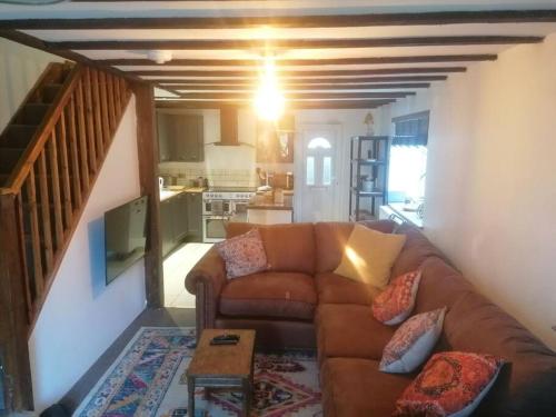 uma sala de estar com um sofá castanho e uma cozinha em The Old Barn, Cosy Townhouse in Leominster em Leominster
