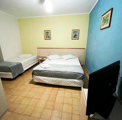 two beds in a room with blue walls at Central Park Hotel São Carlos - Fácil Acesso USP e Industrial in São Carlos