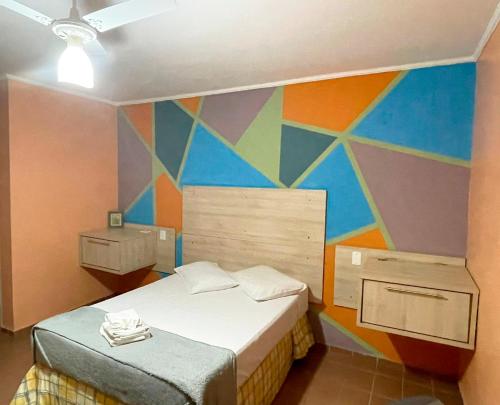1 dormitorio con una pared colorida y 1 cama en Central Park Hotel Residence, en São Carlos