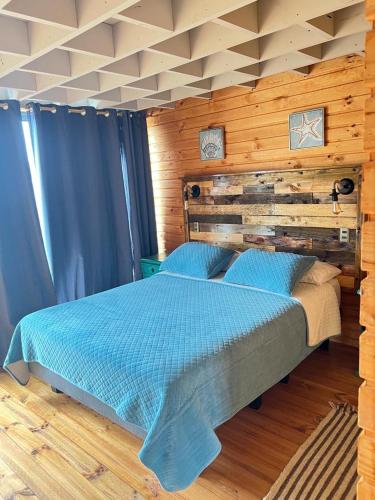 a bedroom with a blue bed in a wooden room at PEZ HOUSE in Pichilemu