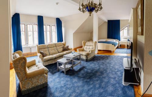 ein Wohnzimmer mit einem Sofa, Stühlen und einem Bett in der Unterkunft Park Hotel Brūzis in Smiltene