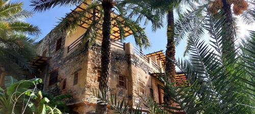 a building with palm trees in front of it at Misfah Old House in Misfāh