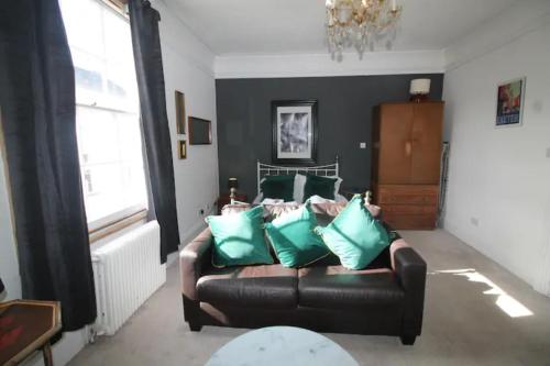 a living room with a leather couch with green pillows at City Centre Bolt Hole Exeter in Exeter