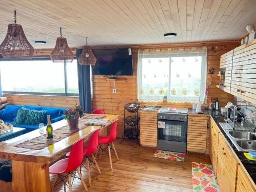 a kitchen with a table and red chairs in a room at PEZ HOUSE in Pichilemu