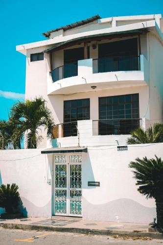 a white building with a gate and palm trees at HOTEL MANTA BEACH MADRIGAL in Manta