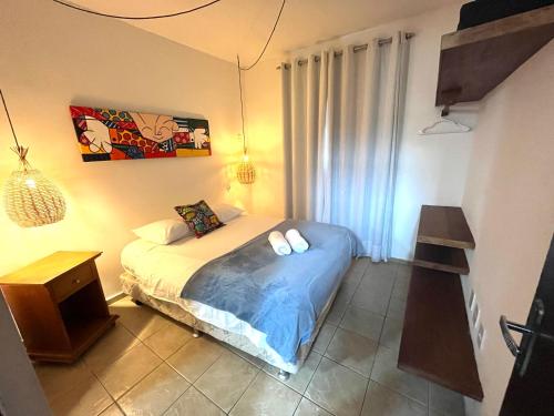 um quarto com uma cama, uma mesa e uma fotografia em Charmoso Chalé Triplex - Centro da Pipa em Pipa