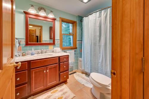 W łazience znajduje się umywalka, toaleta i lustro. w obiekcie Spacious Tolland Home with Deck and Screened Porch! w mieście Sandisfield