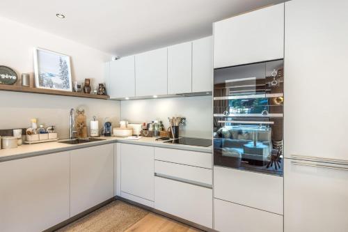 - une cuisine blanche avec des placards blancs dans l'établissement Appartement du Cerf - Welkeys, à Megève