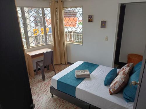 1 dormitorio con cama, escritorio y ventana en coliving el jardin de envigado sede san marcos, en Envigado
