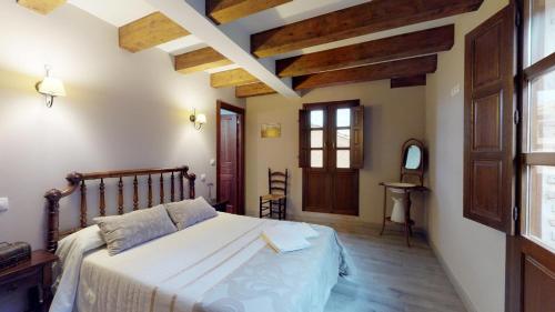 a bedroom with a large bed with wooden beams at Casa rural El Veredero in Castrojeriz