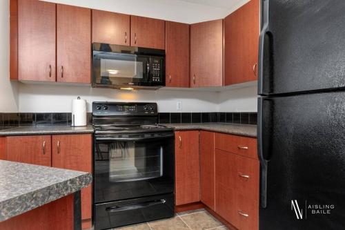 a kitchen with a black refrigerator and wooden cabinets at Light N Airy, Pool, Hot Tub, Pets, Ground Floor in Invermere