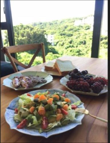 two plates of food on a wooden table with fruit at セナはハウスB02 in Yomitan